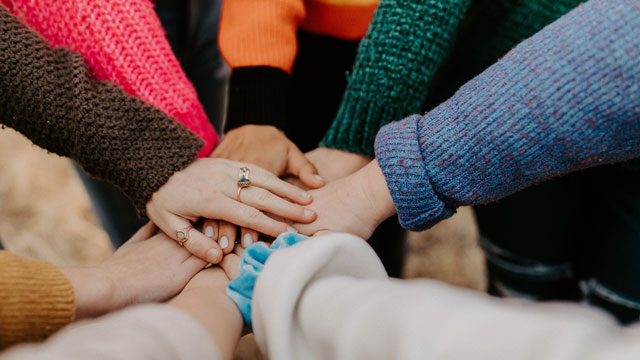 group of friends with hands together in a circle
