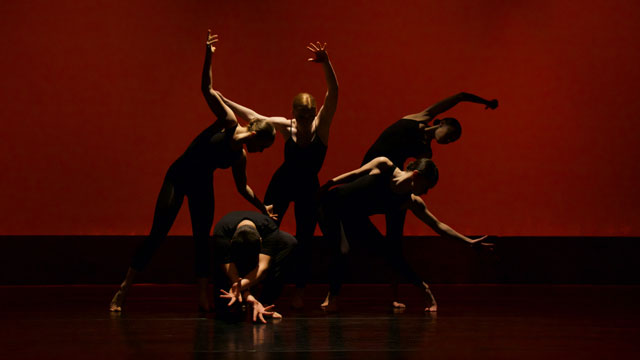 five dancers on a darkened stage