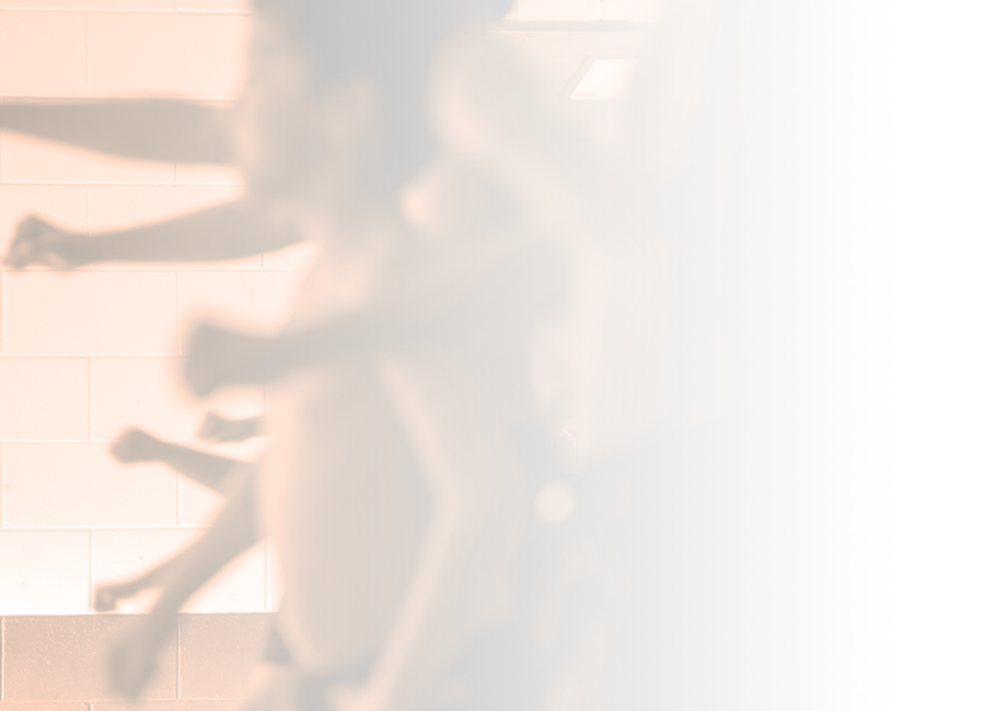 An out of focus photograph showing a group of young boys performing a haka shirtless. Their faces are not shown. 