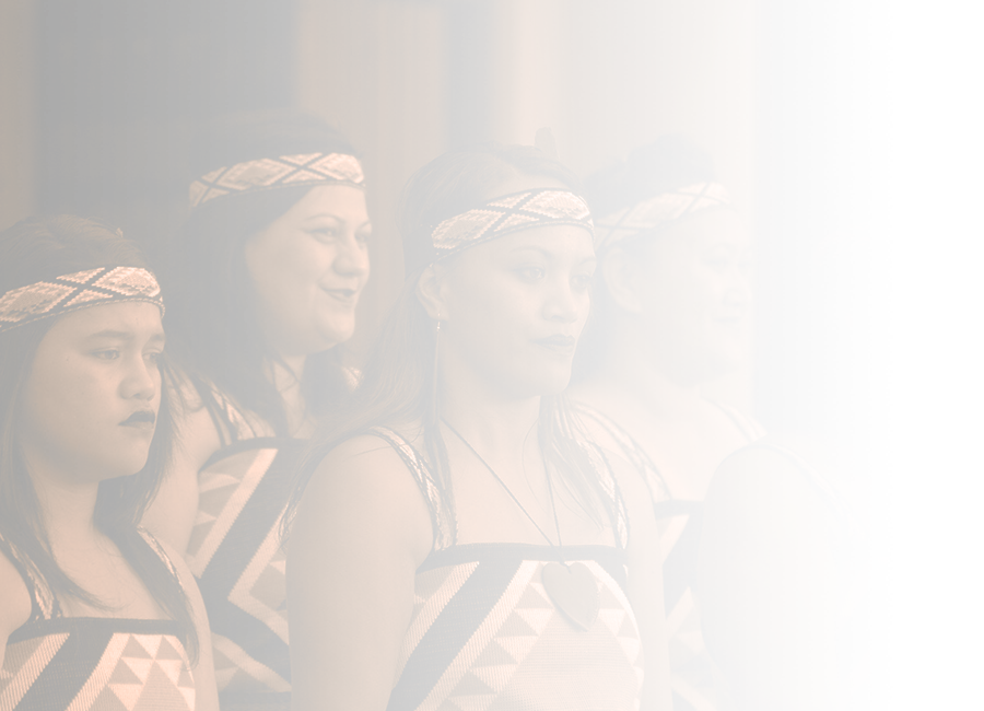 A chest-up photograph of five Māori women in kapa haka performance attire. 