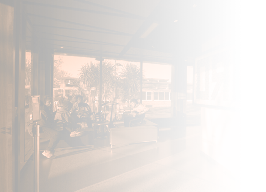 A photograph of five students sitting practising music, with the leftmost student playing a guitar, and another student playing a drumkit. 