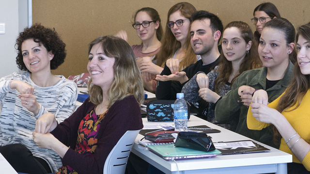 A group of students sitting at desks and signing in unison