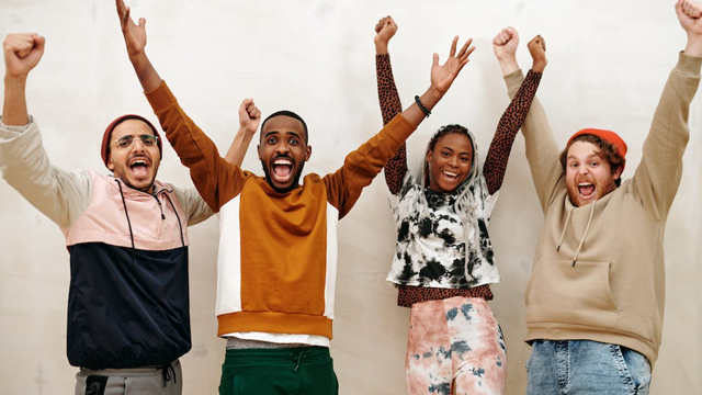 A group of four people with their arms raised in celebration