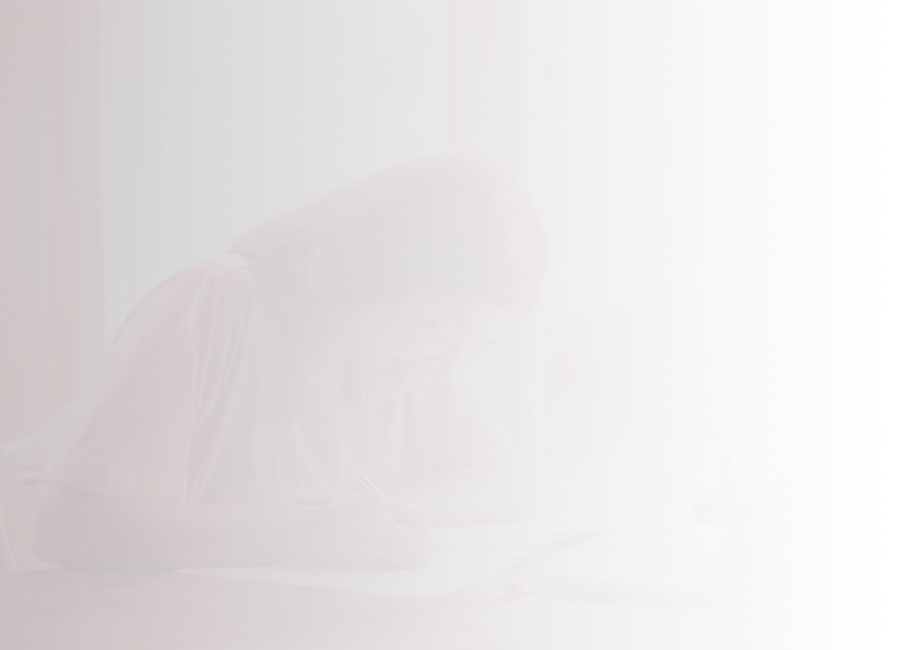 A teen in a brightly coloured tee shirt writes in a notebook