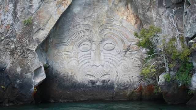 The tattooed face of Ngātoroirangi carved in the rockface above Lake Taupō, by master carver Matahi Whakataka-Brightwell.